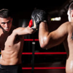 Latin boxer and his coach doing some sparring in the ring